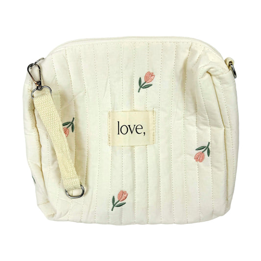 Cream-colored quilted bag with floral embroidery and 'love' tag on a white background