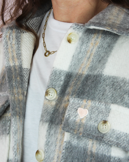 Close-up of a person wearing a plaid coat with heart patterns and buttons.
