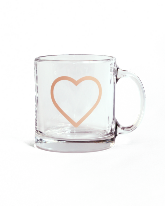 Clear glass mug with a coral pink heart design on a white background