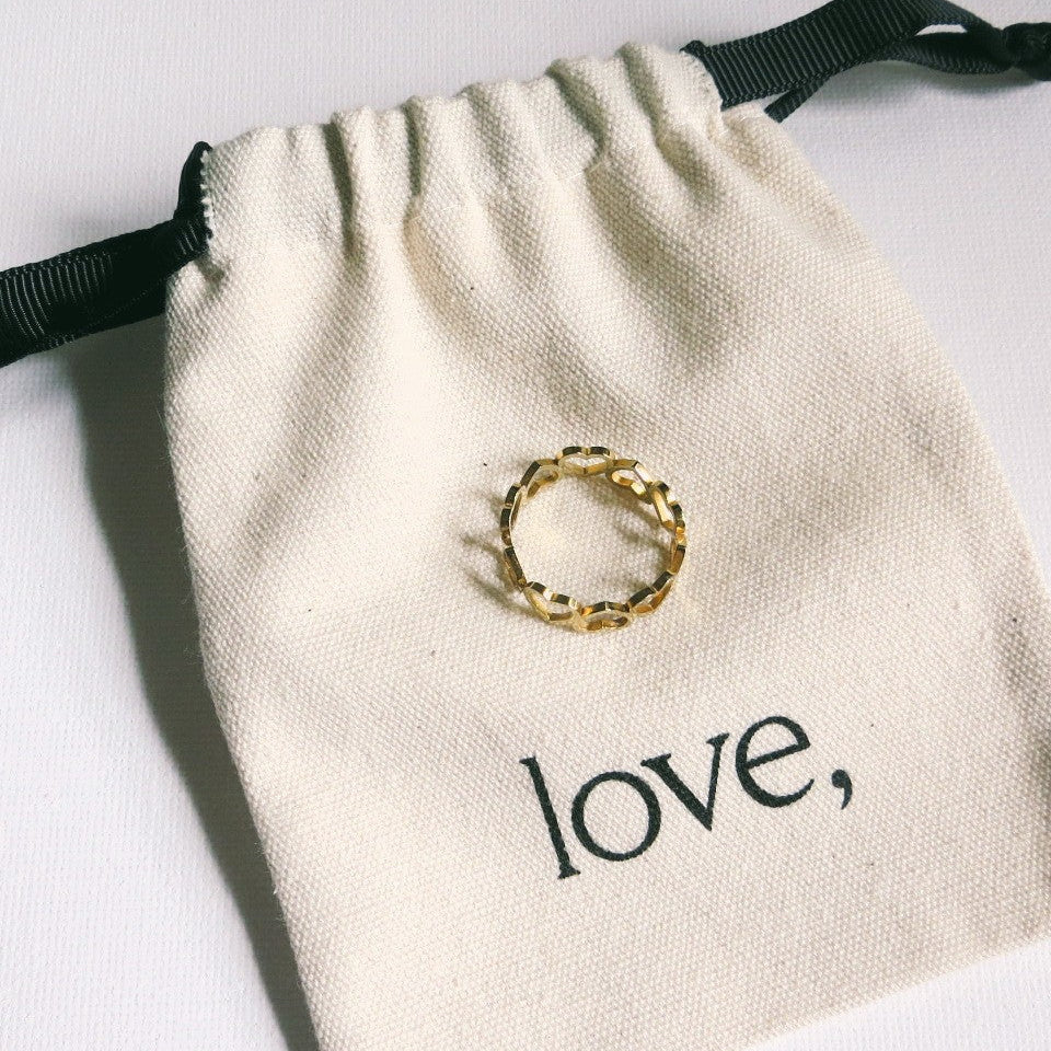 Gold ring on a beige drawstring bag with 'love' printed on it.