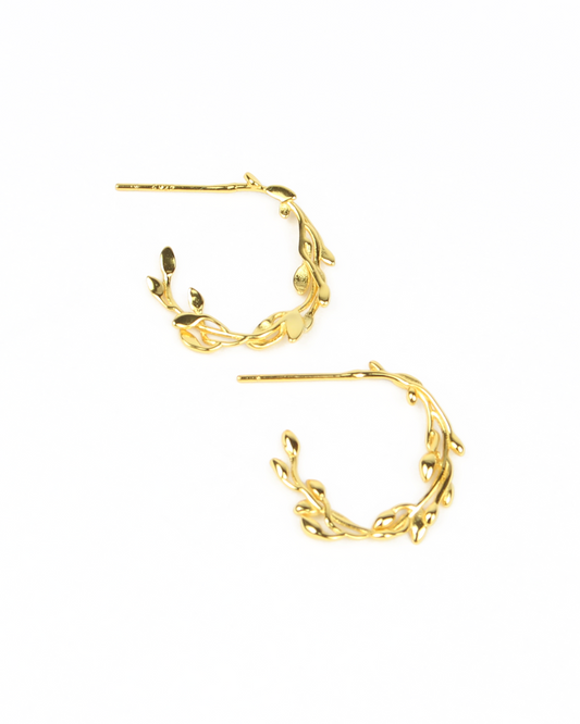 Gold hoop earrings with leaf-like designs on a white background