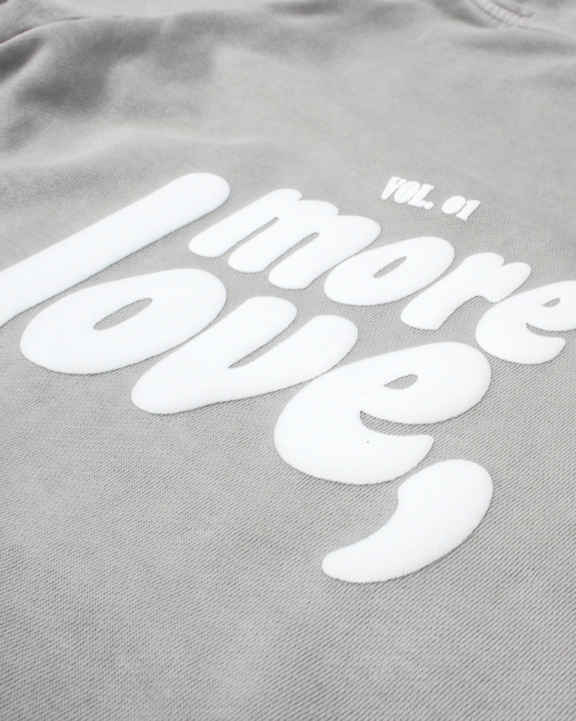 close up of grey hoodie on a white background with text more love,