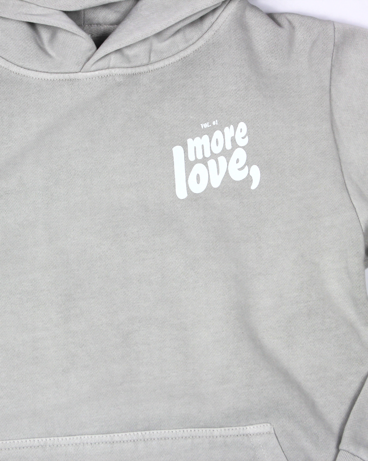 close up of grey hoodie on a white background with text more love,