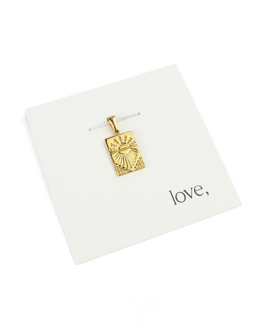 gold charm on a card on a white background