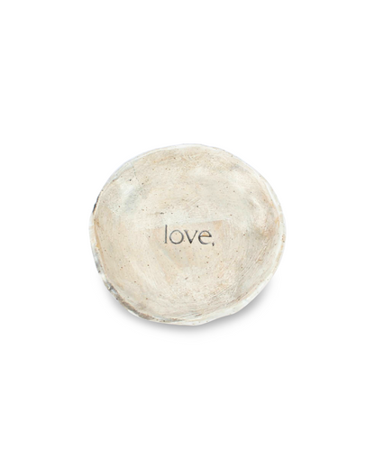 Round ceramic dish with 'love,' debossed on a white background