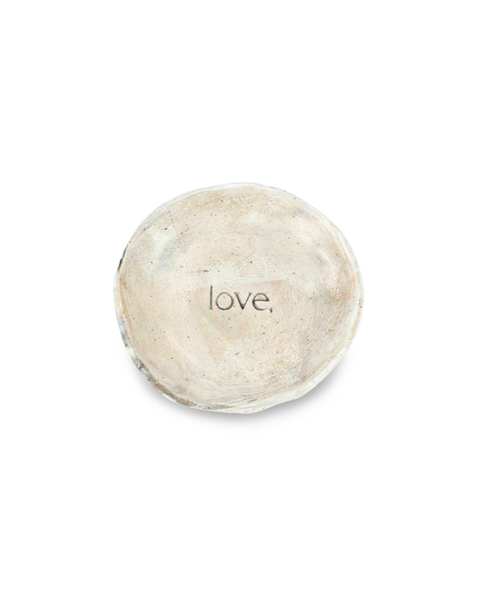 Round ceramic dish with 'love,' debossed on a white background